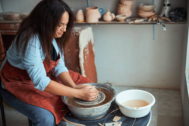 Beautiful woman ceramist making pottery in workshop - Photo, Image