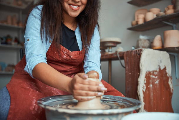 Joyful young woman making pottery in workshop - Photo, Image