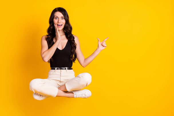 Full length body size photo of woman sitting on chair amazed pointing blank space touching cheek isolated on bright yellow color background - Fotografie, Obrázek