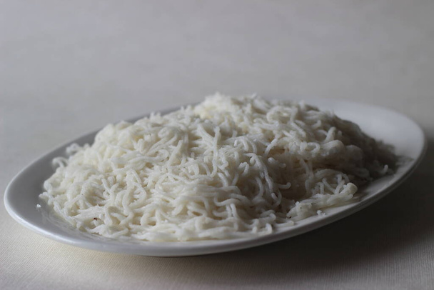 Tolvas de cuerda, un plato de fideos de arroz al vapor. Plato de desayuno popular de Kerala, conocido localmente como idiyappam. Disparo sobre fondo blanco. - Foto, Imagen