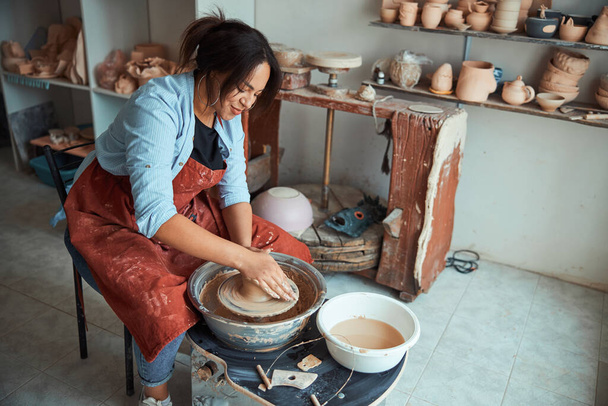 Charming female ceramist making pottery in workshop - Photo, Image