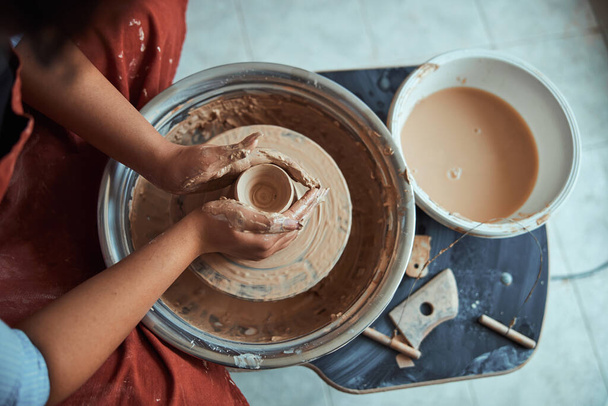 Manos de alfarero hembra lanzando olla de barro en la rueda de cerámica - Foto, Imagen