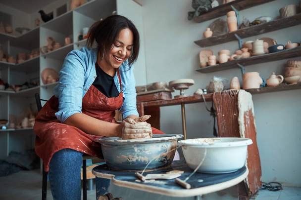 Χαρούμενη γυναίκα αγγειοπλάστη κατασκευή κεραμικών στο εργαστήριο - Φωτογραφία, εικόνα