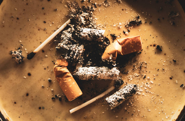 Nahaufnahme von weggeworfenen Zigarettenkippen mit Asche - Foto, Bild