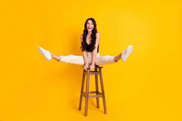 Full body photo of young excited girl happy positive smile playful fooling sit chair isolated over yellow color background - Foto, Imagen
