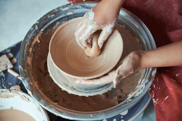 Feminino oleiro mãos limpando tigela de argila com esponja - Foto, Imagem