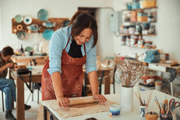 Artesana alegre en delantal trabajando en taller de cerámica - Foto, imagen