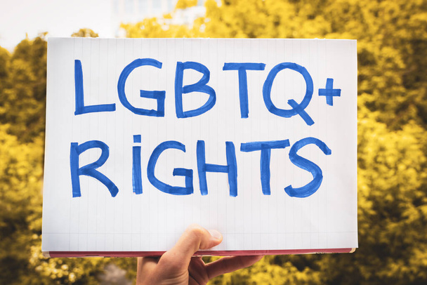 青い文字のポスターLGBTQの権利ぼやけた木の背景に手をつないで。レズビアン、ゲイ、バイセクシャル、トランスジェンダーの人々の権利のデモです。多様性と人権の概念は - 写真・画像