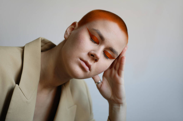 Portrait of beautiful bald woman with closed eyes. Makeup in orange colour. - Zdjęcie, obraz