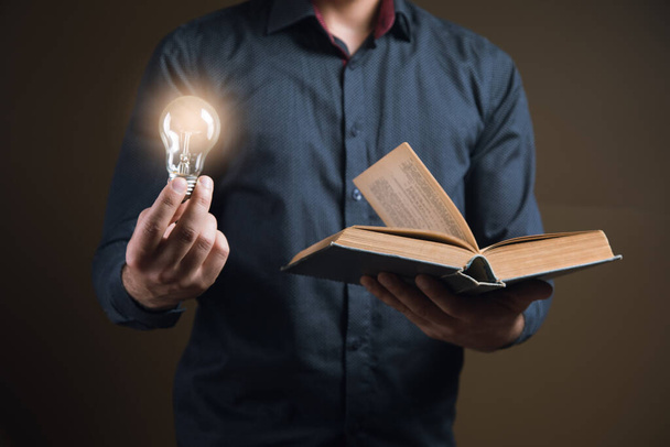 Un homme tenant un livre ouvert et une ampoule. idée de concept d'un livre - Photo, image