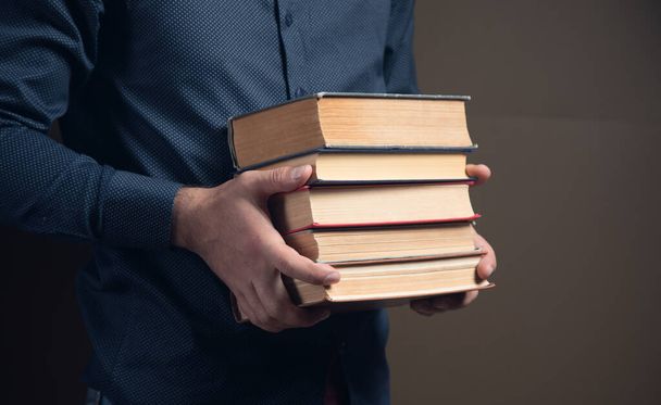 man holding books in his hands on brown background - Photo, Image