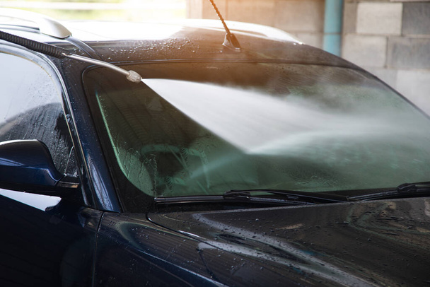 un hombre lava su coche con agua - Foto, Imagen