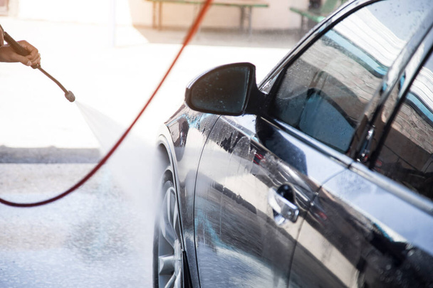 un uomo lava la sua auto con acqua - Foto, immagini