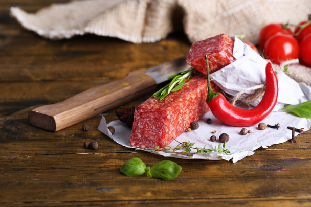 Tasty salami sausage and spices on wooden background - Foto, Bild