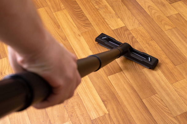 Vacuum cleaner pipe in hand on wooden floor background close up - Photo, Image