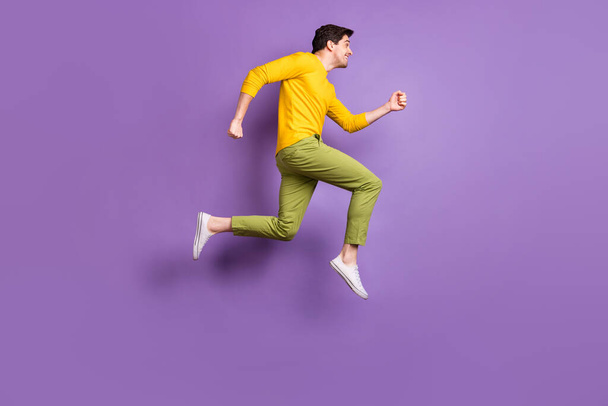 Full length profile side photo of young man happy positive smile jump go walk run hurry sale isolated over violet color background - Фото, изображение
