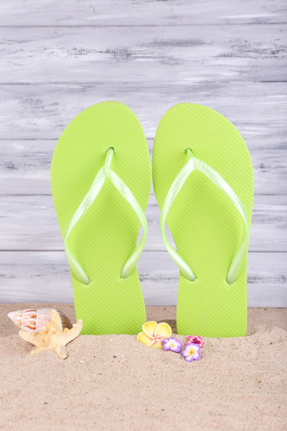 Bright flip-flops on sand, on wooden background - Photo, Image