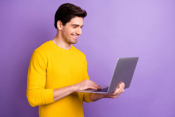 Profile side photo of young businessman happy positive smile look laptop programmer chat isolated over violet color background - Foto, afbeelding
