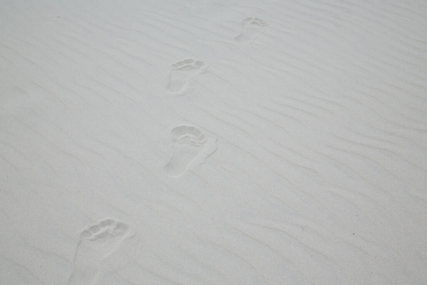 Mezítláb lábnyomok fehér homokon dűnékkel - Fotó, kép