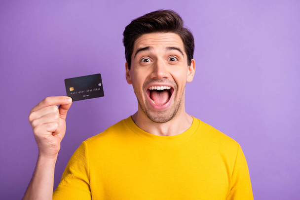 Photo of impressed handsome person hand hold debit card open mouth isolated on violet color background - Φωτογραφία, εικόνα