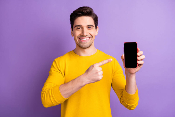 Photo of young happy cheerful smiling good mood positive man point finger at phone advertisement isolated on purple color background - Φωτογραφία, εικόνα