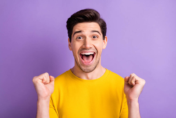 Photo of astonished guy fists up celebrate open mouth yell yeah isolated on pastel violet color background - Photo, Image