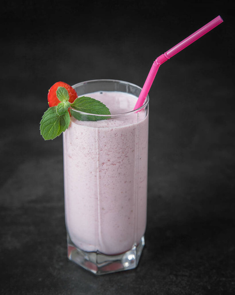 Strawberry smoothie with milk in a glass on a black background .  Homemade strawberry milk shake in a glass  with a mint leaves .  - Фото, изображение
