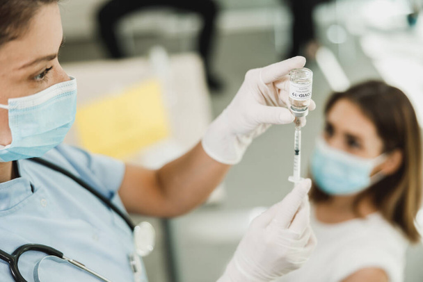 Infirmière tenant la seringue et faisant la dose d'injection de vaccin Covid-19 dans l'épaule du patient féminin portant un masque. - Photo, image