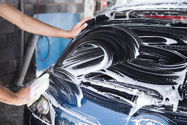Adamın biri arabanın köpüğünü bez parçasıyla siliyor. araba yıkama - Fotoğraf, Görsel