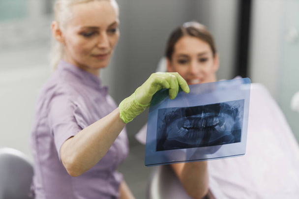 Dentystka i jej młody pacjent patrzą na orthopantomogram podczas wizyty u dentysty. - Zdjęcie, obraz