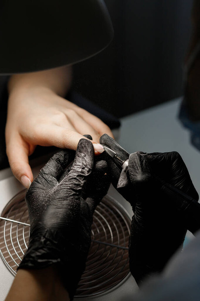 The manicurist makes a manicure with a saw in the salon. close-up - Fotó, kép