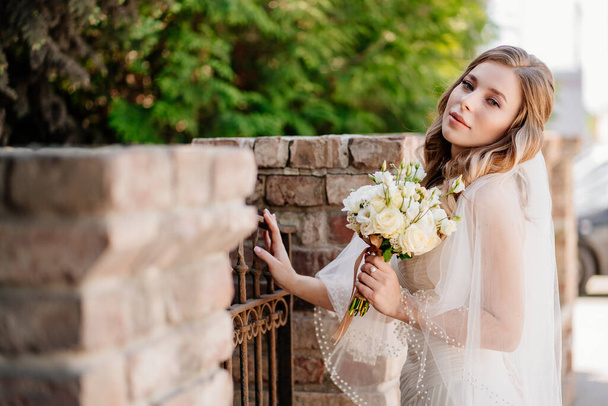 beautiful bride with a bouquet of flowers at the fence. - Foto, immagini
