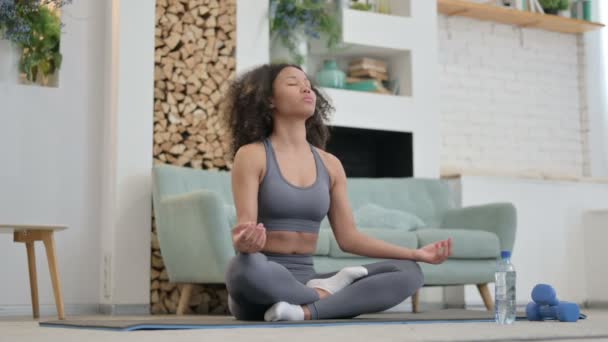 Joven mujer africana meditando en la esterilla de yoga en casa - Metraje, vídeo