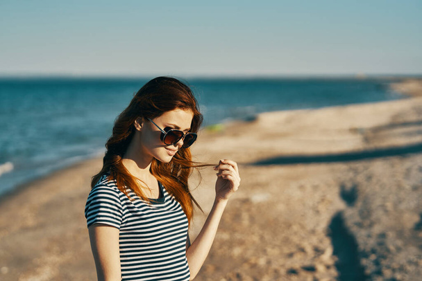 Kobieta w t-shirtach stoi na piaszczystym brzegu plaży w pobliżu morza - Zdjęcie, obraz