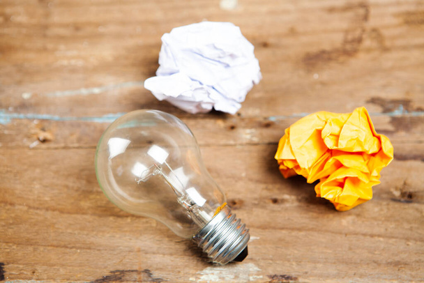 crumpled papers and a light bulb on a wooden table - Photo, Image