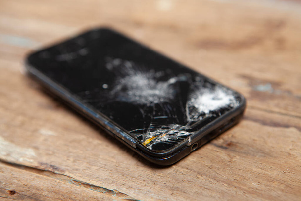 broken smartphone screen on wooden background - Photo, image