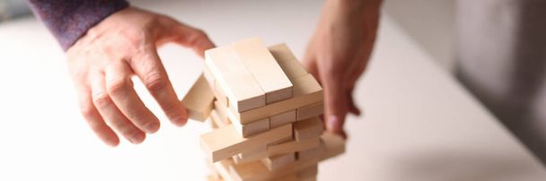 Varias manos alcanzan bloques de madera de la torre de juguete - Foto, imagen
