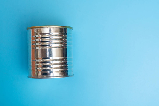 Closed metal can of canned food on a blue background. - Foto, afbeelding