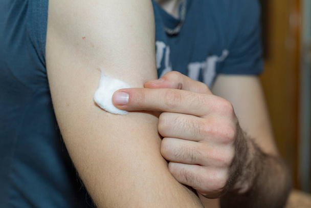 Muž drží rouno na rameni poté, co byl očkován proti koronavirové infekci covid-19 během pandemie. - Fotografie, Obrázek