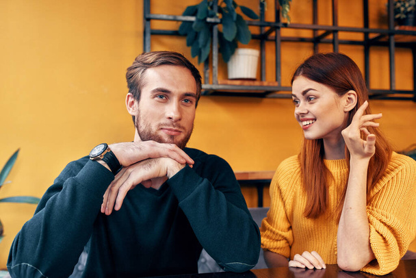 cheerful man and woman gesturing with their hands and sitting at a table in a cafe communication friends a cup of coffee - Foto, Imagem