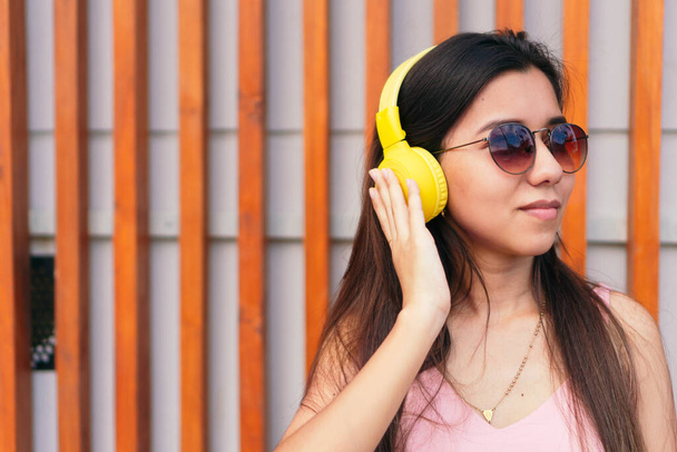 Латинська жінка слухає музику з навушниками на вулиці. - Фото, зображення