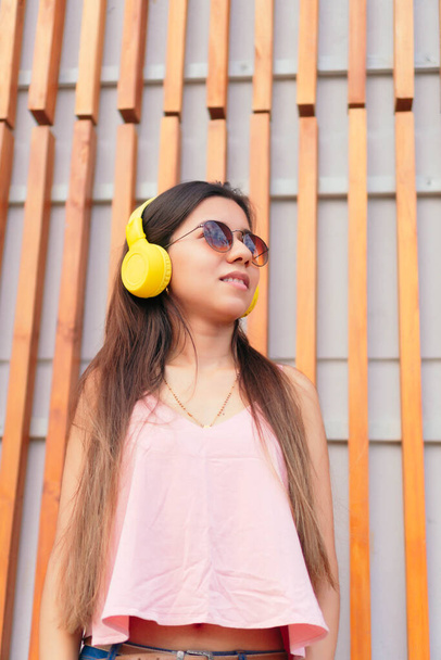 Pretty girl listening to music with her headphones in the street - 写真・画像