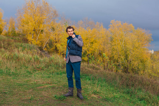 Magas jóképű férfi sétál kint a sárga őszi erdőben a dombon vihar előtt. - Fotó, kép