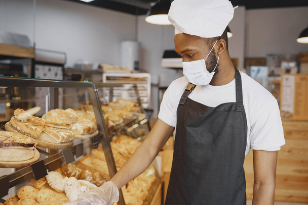 Fine African American man in mask offering pastry - Φωτογραφία, εικόνα