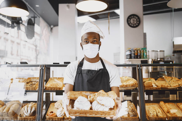 African American baker holding tray of bread in bakery - Photo, image