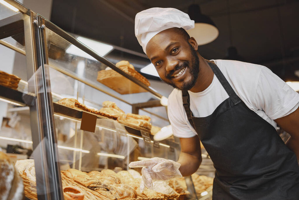 Fine African American man in mask offering pastry - Zdjęcie, obraz