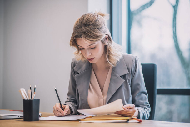 Focused woman taking notes on documents in office - Foto, Imagem