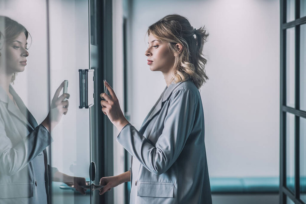 Serious woman opening door with combination lock in office - Foto, Imagem