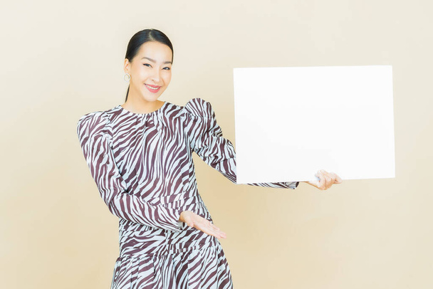 Portrait beautiful young asian woman with empty white billboard on color background - Foto, imagen