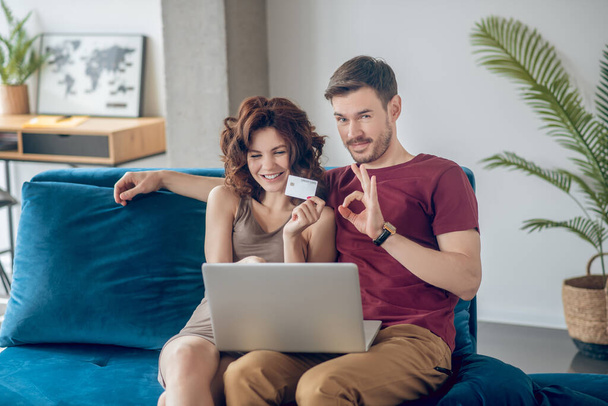 Young couple siting on the sofa and choosing products online - Фото, зображення